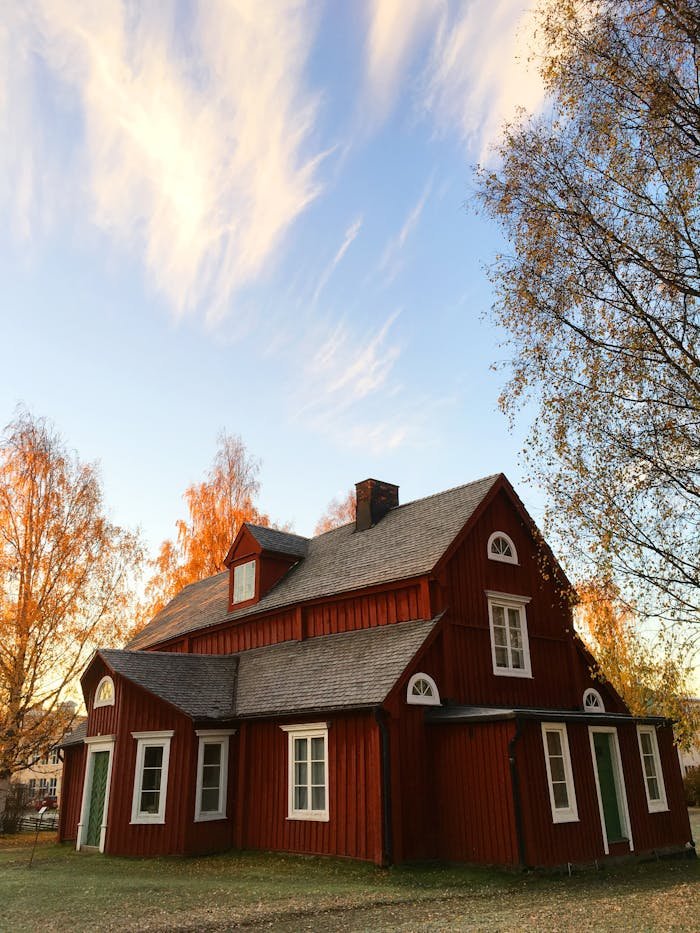 services-03 Picturesque red wooden house in autumn. Traditional Swedish architecture amidst colorful foliage.